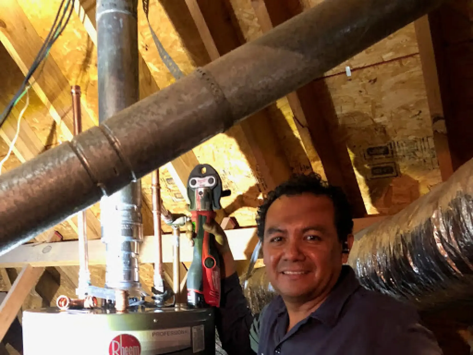 Technician working on a water heater in an attic.