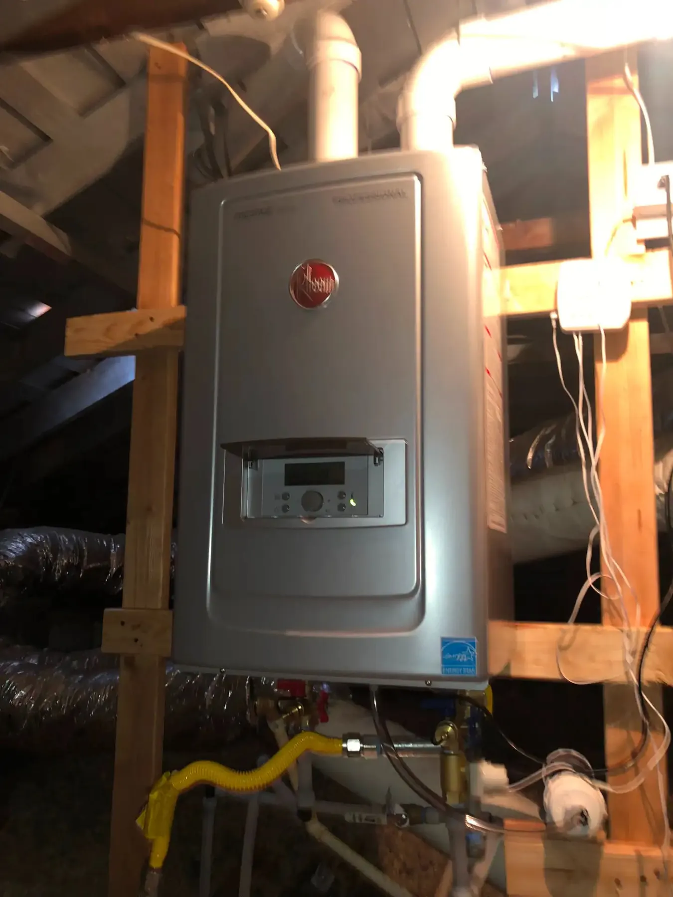 Tankless water heater installation in a home attic with visible plumbing connections.